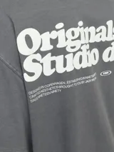 Camiseta Jack & Jones de manga corta, color gris con efecto desgastado, cuello redondo y fit loose. Presenta un pequeño texto estampado en el pecho.