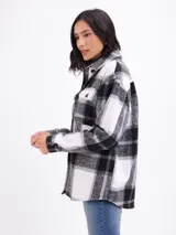 Sobrecamisa de franela con estampado de cuadros grandes en tonos blanco y negro. Presenta cuello camisero, cierre frontal con botones, mangas largas con puños abotonados y bolsillos frontales con solapa.