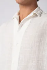 Camisa de manga corta confeccionada en lino, con cuello clásico y cierre frontal de botones. Presenta un corte relajado y textura liviana.