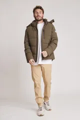 Cazadora acolchada tipo puffer color verde militar, con capucha desmontable, cierre frontal y bolsillos laterales con cierre.