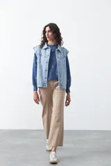 Chaleco de jean en tono celeste claro, con corte recto, cuello camisero, cierre frontal con botones metálicos y costuras visibles.