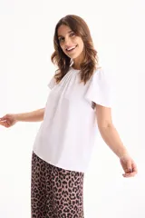 Blusa de manga corta con pliegues en escote redondo, confeccionada en tela crepé de color beige.