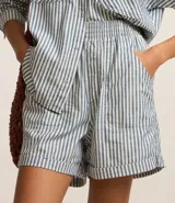 Short femenino de sarga con estampado de rayas verticales en azul y blanco. Cuenta con cintura alta elástica, bolsillos laterales y traseros, y bajo plegado. Confeccionado en 100% algodón.