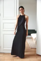 Vestido largo de satén con cuello halter ajustable y hombros descubiertos. Presenta un diseño elegante con espalda detallada en tejido con relieve y bordados perforados. Incluye cierre lateral con cremallera oculta.