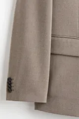Blazer cruzado de corte relajado, color beige, con solapas de pico, cierre de doble botonadura, bolsillos ribeteados con solapa en la parte frontal y abertura en la parte trasera.