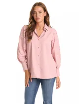 Camisa de color rosado con cuello clásico y cierre frontal de botones. Presenta mangas largas con detalles calados y puños anchos abotonados.