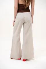 Pantalón color beige de corte wide leg, con bolsillos delanteros y cierre frontal de botón y cremallera.