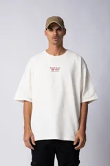 Remera de corte oversize color crudo, con cuello redondo y mangas cortas. Presenta una estampa pequeña en el centro del pecho con la frase 'Fresh from the vine' en color marrón.