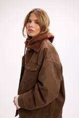 Campera de denim color marrón con diseño vintage, corte relajado y cuello de pana al tono. Presenta cierre frontal con botones metálicos, bolsillos con solapa en el pecho y bolsillos laterales.