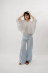 Blusa de lino color blanco, de diseño holgado, manga larga amplia acampanada con detalles de bordado en los puños y cuello redondo.