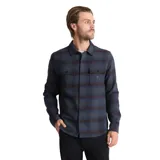 Camisa de manga larga con diseño a cuadros en tonos azul y negro, confeccionada en una mezcla de algodón y poliéster. Presenta cuello clásico, cierre frontal con botones y dos bolsillos en el pecho con solapa.