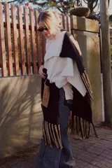 Ruana tejida en lana con bloques bicolor y detalles en color camel. Presenta bolsillos delanteros y terminación con flecos.