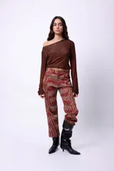 Pantalón de corte recto y largo al tobillo, con estampado de espiga en tonos oscuros y líneas rojas. Presenta tiro medio y cierre frontal.