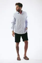 Camisa celeste a rayas verticales blancas, de corte clásico, manga larga y cuello abotonado.