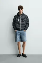 Bermuda de jean con corte regular fit, confeccionada en denim de algodón con elasticidad. Presenta diseño de cinco bolsillos, efecto lavado y cierre frontal con cremallera y botón.