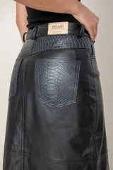 Pollera midi de cuero ovino con diseño tipo jean, cierre frontal con botón y tajo central.