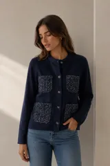 Chaqueta de punto color azul marino con cuello redondo, cierre frontal de botones y cuatro bolsillos delanteros con textura jaspeada en contraste.
