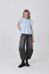 Blusa celeste de viscosa con diseño holgado, cuello a la base con detalle de volados, mangas cortas con volados y detalle de punto smock en el pecho.