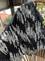 Chaleco negro con lentejuelas plateadas y forro negro.