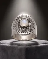 Anillo de plata 925 con diseño ovalado labrado y piedra de la luna central. Presenta detalles de relieve y texturas circulares en toda la superficie.
