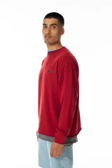 Buzo rojo de jersey doble 100% algodón, con corte levemente boxy y logo frontal serigrafiado en estilo graffiti. Costuras negras visibles y cuello redondo con ribete azul. Hecho en Uruguay.