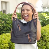 Cartera estilo hobo color marrón, confeccionada en material símil cuero con textura. Presenta dos bolsillos frontales con cierre metálico, apertura superior con cierre y asa corta para el hombro.