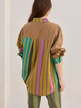Camisa de algodón liviano con diseño de rayas multicolor, corte holgado, cuello camisero, mangas largas y bolsillo frontal.