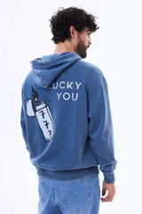 Buzo canguro oversize de felpa color azul, con capucha y estampa gráfica en la espalda que incluye la frase 'Lucky You' y un encendedor con el número 777.