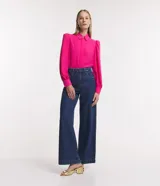 Camisa celeste de crepé con cuello inglés, manga larga abullonada y abotonadura frontal.