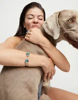 Pulsera rígida plateada con dos cristales facetados triangulares de color verde en los extremos.