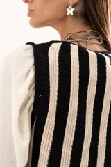 Chaleco tejido a rayas verticales en color negro y crudo, con escote en V y cierre frontal con ganchitos.