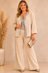 Chaqueta de crepe color beige con diseño abierto, mangas tres cuartos y detalles de lentejuelas plateadas en los bordes frontales y el cuello.