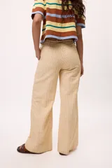 Pantalón recto color amarillo con rayas verticales blancas.