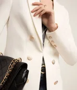 Blazer femenino de sastrería confeccionado en tejido Punto Roma, con cuello solapa, cierre frontal con ganchos y botones decorativos dorados con escudo grabado.