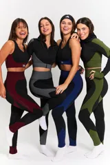 Conjunto deportivo de tres piezas compuesto por campera crop con cierre frontal, top y calza chupín. Presenta un diseño técnico con texturas combinadas en negro y gris, con detalles de paneles laterales rayados y tejido texturizado.