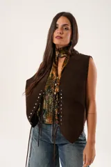 Chaleco marrón de gamuza con cordones laterales y tachas plateadas.