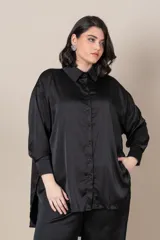 Camisa negra oversize de satén italiano, con cuello clásico, cierre frontal con botones, mangas largas con puños anchos y tajos laterales.