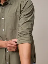 Camisa de manga larga para hombre, confeccionada en algodón con efecto peach (textura suave). Presenta un estampado de cuadros vichy en tonos azul marino y blanco, cuello con botones y un bolsillo de parche en el pecho izquierdo.