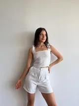 Conjunto de dos piezas compuesto por un top corto de escote cuadrado con breteles anudables y un short de tiro alto con pinzas y cierre frontal, ambos confeccionados en tela sastrera con estampado de rayas verticales finas.