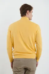 Sweater verde oliva de tejido acrílico con textura similar al cashmere, corte clásico, cuello alto con cierre metálico y tirador de cuerina ecológica.