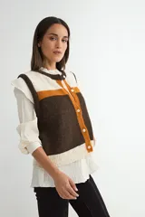 Chaleco tejido de punto con diseño de bloques de color en tonos marrón, naranja y crema. Presenta cuello redondo, cierre frontal con botones y terminaciones acanaladas en el ruedo y sisas.