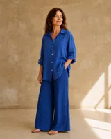 Camisa de lino color azul francia, de corte holgado, con mangas largas regulables, bolsillo ojal en el pecho y botones de nácar en la parte frontal.