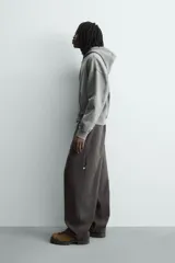 Pantalón de corte relaxed fit confeccionado en algodón, color gris oscuro. Presenta bolsillos delanteros, bolsillos laterales tipo cargo en las perneras y cierre frontal con cremallera y botón.
