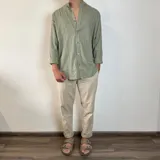 Camisa de manga larga en tejido de lino, color blanco, con cuello mao y cierre frontal de botones. Presenta un corte oversize y mangas con puños doblados.
