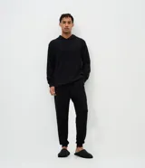 Pantalón de pijama tipo jogger, color negro, con cintura elástica ajustable mediante cordón, bolsillos laterales y puños en los tobillos.