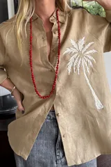 Camisa blanca de lino con bordado de pulpo azul en el pecho, de corte recto y manga larga.