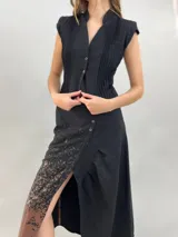 Chaleco negro de lana con diseño estructurado, cuello alzado y detalle de alforzas verticales en los laterales. Presenta cierre frontal con botones metálicos y corte a la cintura.