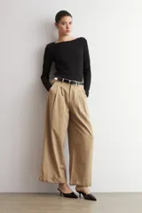Pantalón pinzado de corte ancho, color beige, con bolsillos laterales y botamanga con vuelta.