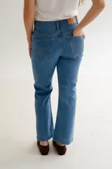 Jean de corte recto y tiro medio, confeccionado en denim azul clásico. Presenta diseño de cinco bolsillos con costuras reforzadas y cierre frontal con botón metálico.