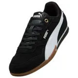 Championes Puma modelo Bella Donna, de diseño urbano y deportivo en color negro con la franja lateral característica en blanco. Presentan una suela de goma color caramelo con excelente tracción y detalles en dorado en los ojales de los cordones.